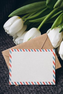 Bahar kompozisyonu, bir kartpostal ve bir buket beyaz lale, yakın plan. Boş posta kartı ve bir buket taze lale çiçeği, kopyalama alanı..