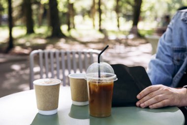 Bahçedeki bir kahve dükkanının terasında kahve içen bir grup arkadaş. İnsanlar buzlu, köpüklü kahve içiyor. Espresso ile portakal suyunu birleştiren ferahlatıcı bir içecek. Moda yaz kahvesi..