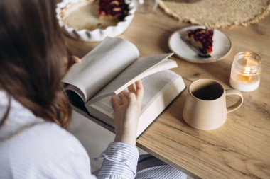 Sıcak bir mutfakta kahvaltı ederken İncil okuyan bir kadın. Ilık sabah ışığı, inancın, yansımanın ve günlük bağlılığın huzurlu bir atmosferini yaratıyor..