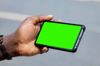 Siyah Afrikalı el ele tutuşup yatay olarak boş ekran cep telefonu kullanıyor.