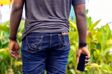 İnşaat alanında akıllı telefon tutan Afrikalı genç bir adam.