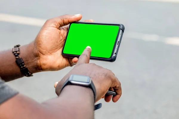 African black man pointing finger at blank screen smart phone, with smart watch street lifestyle, blurred background