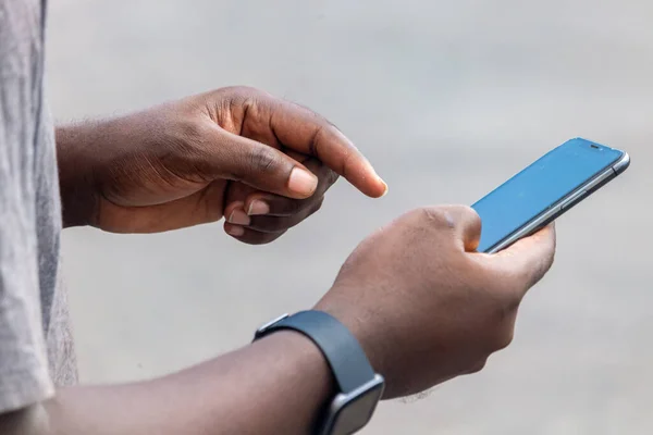 Afrikalı siyahi adam boş ekranlı akıllı telefonu işaret ediyor, akıllı saat sokak yaşam tarzı, bulanık arka plan
