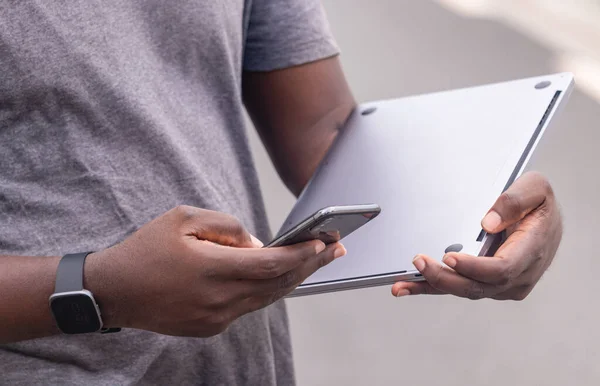 Kentsel ortamdayken Afrikalı adam cep telefonundan mesaj okuyor.