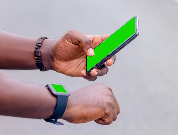 African black man pointing finger at smart phone in city , texting on mobile phone, sparkling street lifestyle, blurred background