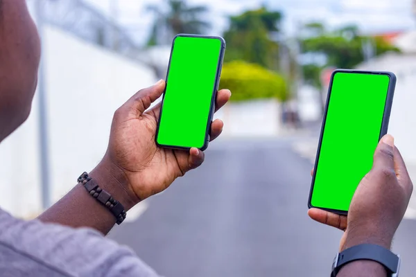 Kenardan, şehirdeki bir şantiyede akıllı telefon tutan genç bir Afrikalı adamın eli.