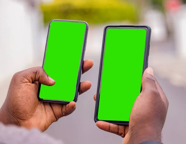 Kenardan, şehirdeki bir şantiyede akıllı telefon tutan genç bir Afrikalı adamın eli.