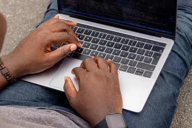 Dizüstü bilgisayarıyla çalışan Afrikalı bir web geliştiricisinin el resmi,