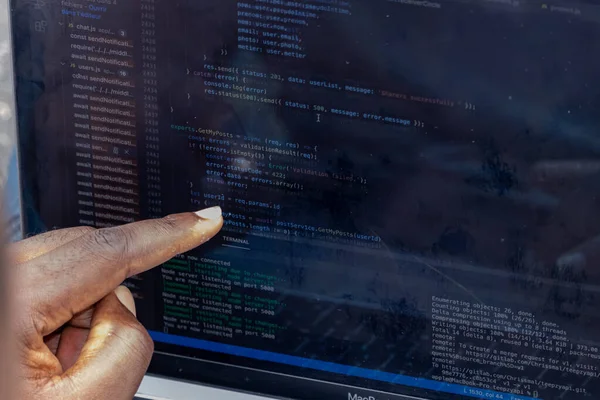 Afrika web geliştiricisinin el portresi bilgisayar kodunu işaret ediyor.