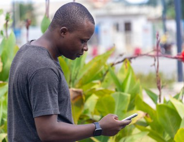 Genç bir Afrikalı, şehir bahçesindeki bir telefon görüşmesinden iyi haberler alıyor.