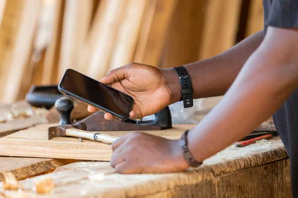 Cep telefonu tutan profesyonel bir marangozun yakın çekimi. Takıl