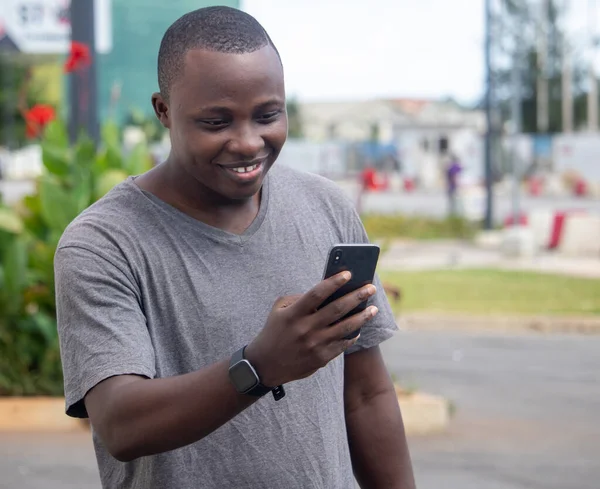 Genç bir Afrikalı, şehir bahçesindeki bir telefon görüşmesinden iyi haberler alıyor.