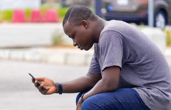 Genç bir Afrikalı, şehir bahçesindeki bir telefon görüşmesinden iyi haberler alıyor.