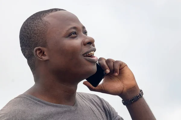 Genç bir Afrikalı, şehir bahçesindeki bir telefon görüşmesinden iyi haberler alıyor.
