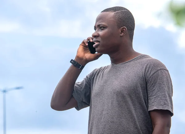 Genç bir Afrikalı, şehir bahçesindeki bir telefon görüşmesinden iyi haberler alıyor.