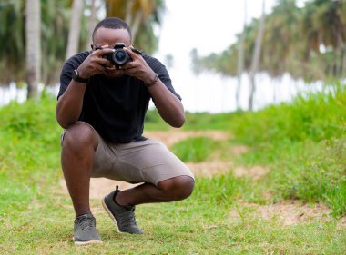 Genç bir Afrikalı eğlence için fotoğrafçılık yapıyor ve bir Afrika köyünde kendini adamış..