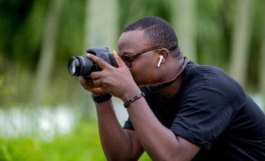 Genç bir Afrikalı eğlence için fotoğrafçılık yapıyor ve bir Afrika köyünde kendini adamış..