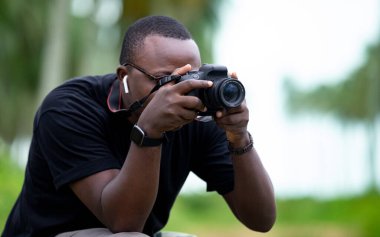 Genç bir Afrikalı eğlence için fotoğrafçılık yapıyor ve bir Afrika köyünde kendini adamış..