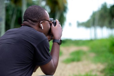 Genç bir Afrikalı eğlence için fotoğrafçılık yapıyor ve bir Afrika köyünde kendini adamış..