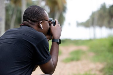 Genç bir Afrikalı eğlence için fotoğrafçılık yapıyor ve bir Afrika köyünde kendini adamış..