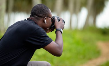 Genç bir Afrikalı eğlence için fotoğrafçılık yapıyor ve bir Afrika köyünde kendini adamış..