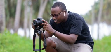 Genç bir Afrikalı eğlence için fotoğrafçılık yapıyor ve bir Afrika köyünde kendini adamış..