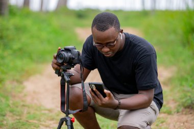 Genç bir Afrikalı eğlence için fotoğrafçılık yapıyor ve bir Afrika köyünde kendini adamış..