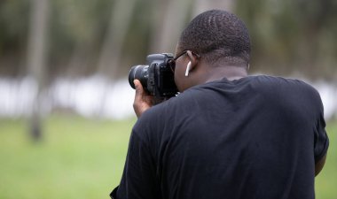 Genç bir Afrikalı eğlence için fotoğrafçılık yapıyor ve bir Afrika köyünde kendini adamış..