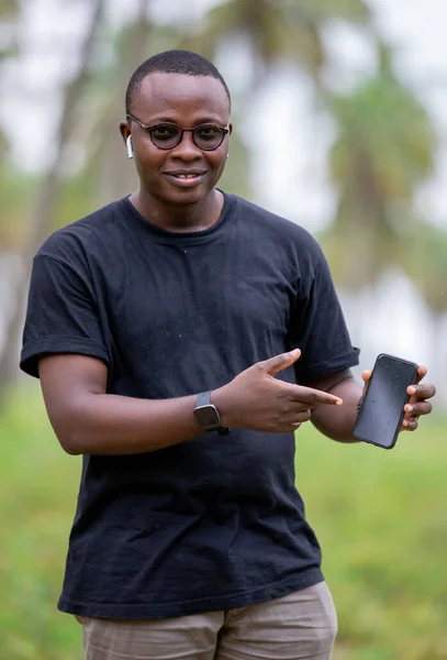 Genç Afrikalı Tarım Mühendisi tarım alanında boş ekran akıllı telefon kullanıyor. bitki büyümesini izlemek için.