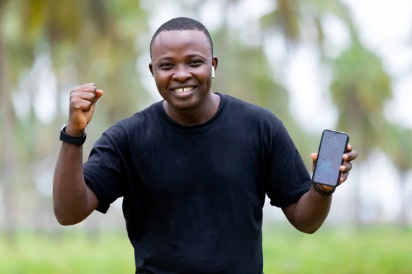 Afrika 'daki köyün neşeli, gülümseyen siyahi Afrikalı genci boş ekranı işaret ediyor..