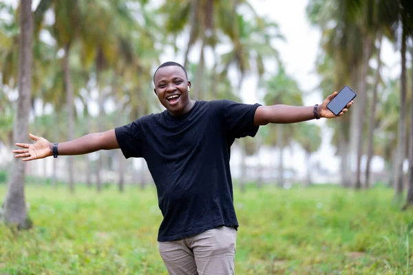 Afrika 'daki köyün neşeli, gülümseyen siyahi Afrikalı genci boş ekranı işaret ediyor..