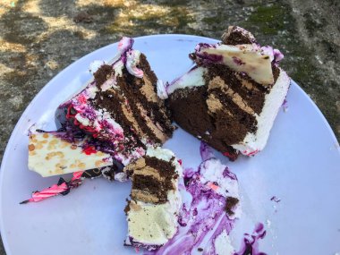 Beyaz bir tabakta iki dilim karışık doğum günü pastası