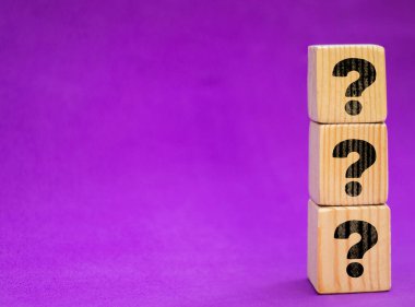 Mor masa ve arka planda soru işaretleri olan tahta küpleri. Metin için boşluk