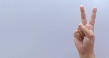 Beyaz arka planda izole edilmiş genç bir kadın zafer işareti gösteriyor. Yakından iki numaralı el parmağı beyaz arka planda izole edilmiş.