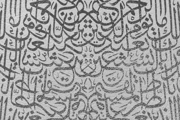 Beyaz bir duvarda, Arapça kaligrafi duvar kâğıdı ve birbirine kenetlenmiş siyah arka plan altyazıları var.