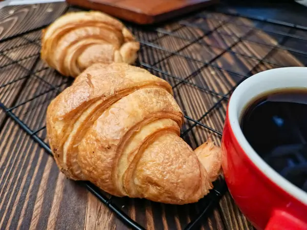 Soğutma rafında üç kruvasan, bir fincan sade kahvenin yanında..