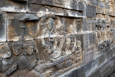 Taş döşemeler, tarihi bir tapınak duvarında antik figürleri ayrıntılı bir şekilde tasvir eder..
