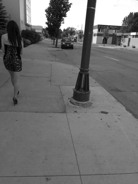 一个漂亮的年轻女子走在城市街道上的黑白照片 — 图库照片