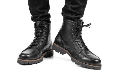 Pair of black leather boots, dress boots for men, men ankle high boots. Black brogue boots on a white background. Men fashion in leather boots. Man's legs in black jeans and brown leather boots.