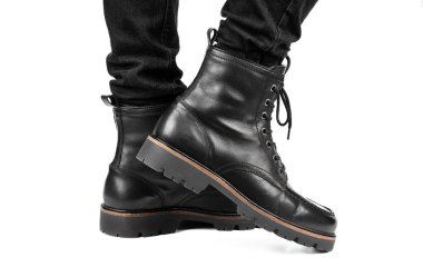 Pair of black leather boots, dress boots for men, men ankle high boots. Black brogue boots on a white background. Men fashion in leather boots. Man's legs in black jeans and brown leather boots.