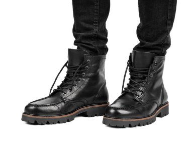 Pair of black leather boots, dress boots for men, men ankle high boots. Black brogue boots on a white background. Men fashion in leather boots. Man's legs in black jeans and brown leather boots.