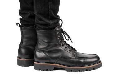 Pair of black leather boots, dress boots for men, men ankle high boots. Black brogue boots on a white background. Men fashion in leather boots. Man's legs in black jeans and brown leather boots.
