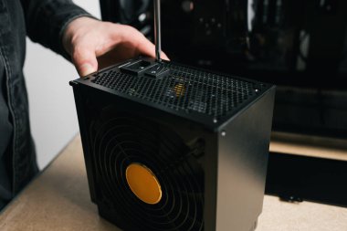 Bir bilgisayar teknisyeni bir bilgisayar güç kaynağı kuruyor. PC monte ediliyor