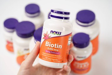 Dnipro, Ukrayna - 09.09.2023: Bir şişe Biotin 5,000 mcg kadın elinde. Şimdi Gıda, bir Biotin Vejetaryen gıda takviyesi.