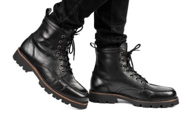 Pair of black leather boots, dress boots for men, men ankle high boots. Black brogue boots on a white background. Men fashion in leather boots. Man's legs in black jeans and brown leather boots.