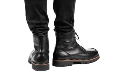Pair of black leather boots, dress boots for men, men ankle high boots. Black brogue boots on a white background. Men fashion in leather boots. Man's legs in black jeans and brown leather boots.