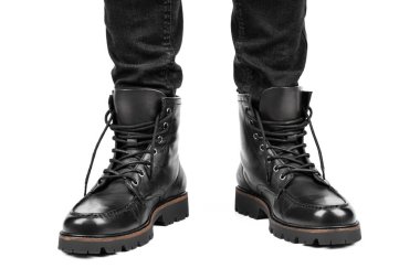 Pair of black leather boots, dress boots for men, men ankle high boots. Black brogue boots on a white background. Men fashion in leather boots. Man's legs in black jeans and brown leather boots.
