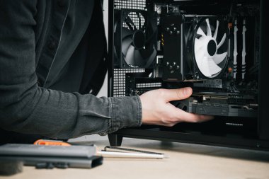 Bir bilgisayar teknisyeni bir bilgisayar güç kaynağı kuruyor. PC monte ediliyor