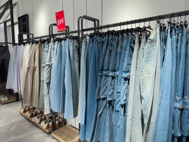 Bir giyim mağazasında askıda asılı kot pantolon ya da kot pantolon. Bir giyim mağazasında satılık moda eşyaları koleksiyonu. Tekstil endüstrisi. Mavi kot pantolon. Satış, alışveriş, gardırop