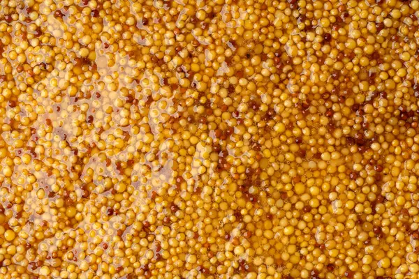 Metal kaşıkta Fransız Dijon hardalı, hardal taneciklerinin arka planda üst görünümü. Gastronomi konsepti, organik gıda. Sos. 